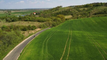 Cyclist riding countryside road by river, aerial panning, Zaton Dolna