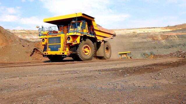 Yellow dump truck in a coal mine. The dump truck drives through the quarry. Large dump truck in a coal mine
