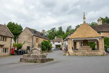honey coloured Cotswold stone houses and market cross in Castle Combe Wiltshire England often named...