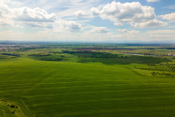 Aerial landscape view of green cultivated agricultural fields with growing crops on bright summer day