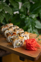 Japanese cuisine. Rolls with sauce on a wooden plate
