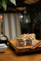Japanese cuisine. Rolls with sauce on a wooden plate

