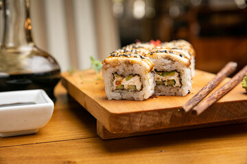 Japanese cuisine. Rolls with sauce on a wooden plate
