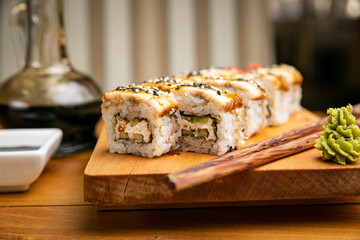 Japanese cuisine. Rolls with sauce on a wooden plate

