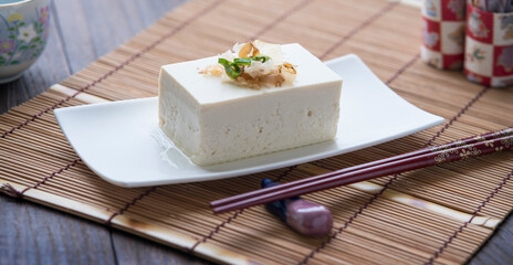 tofu in a white plate on a wooden table. Tofu on a plate in japanese style - obrazy, fototapety, plakaty