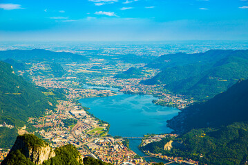 The city of lecco, shot from above, by day, with the surrounding mountains.
