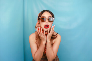 Retro concept of a young Asian woman expressing her sad hysterical face isolated by a blue background - obrazy, fototapety, plakaty