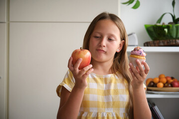 the girl chooses between a cupcake and an apple
