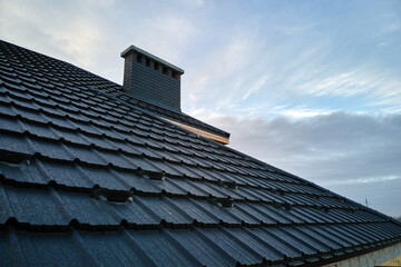 Snow guard for safety in winter on house roof top covered with steel shingles. Tiled covering of building