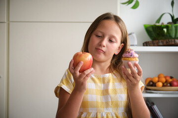 the girl chooses between a cupcake and an apple