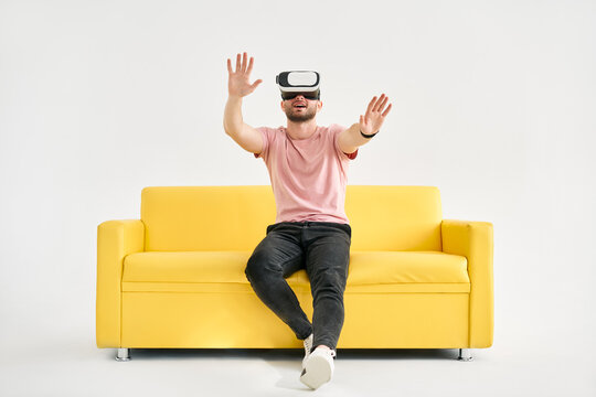 Young man in virtual reality headset playing video games and trying to touch something with hands