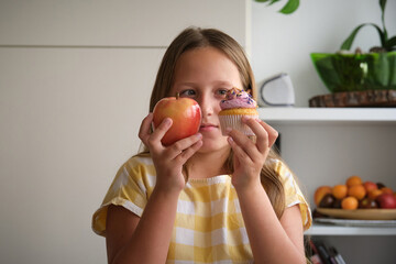 the girl chooses between a cupcake and an apple