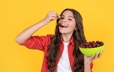 positive teen girl eat cherry bowl on yellow background
