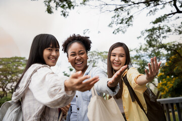 Diversity of happy woman student holding hand and showing follow me with their friends at natural outdoors at public park. Prepare for college and happy in university concept. 