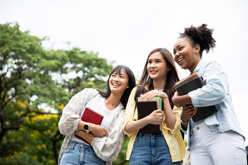 Diversity of happy woman student holding books and looking at natural outdoors at park. Prepare for college and university concept. Informal education and natural research