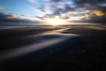 Scenic moving sand dunes at the beach of Amrum island Germany on a windy evening during sunset with drifting clouds