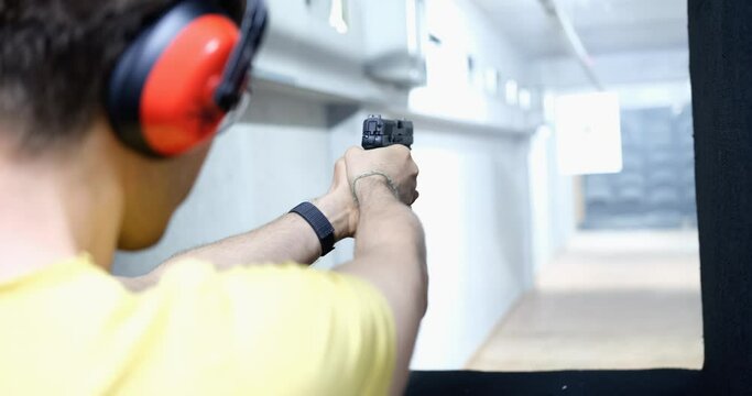 Man shoots a pistol at target in indoor range