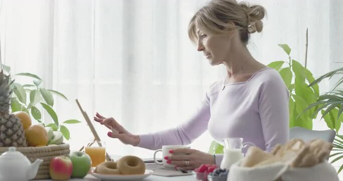 Woman having breakfast and using her tablet