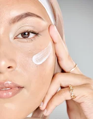 Poster Portrait of a young Muslim woman wearing a hijab or headscarf applying a cream moisturizer on her flawless skin while showing her eyelash extensions while. Applying cosmetics to maintain healthy skin © Jade Maas/peopleimages.com