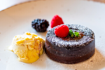 Chocolate fondant (cupcake) with raspberries, ice creme and powdered sugar placed on plate