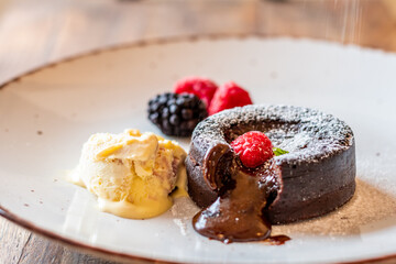 Chocolate fondant (cupcake) with raspberries, ice creme and powdered sugar placed on plate