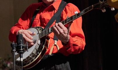 Closeup shot of a male musician playing the banjo in front of a microphone