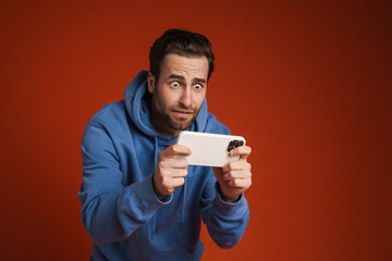 Young shocked man playing online game on mobile phone