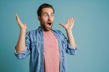 Young white man wearing shirt expressing surprise at camera