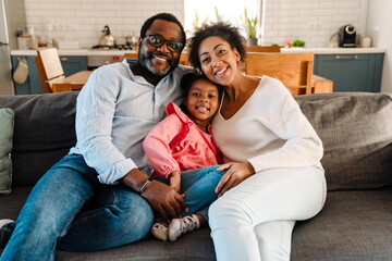 African american family smiling and sitting on sofa at home