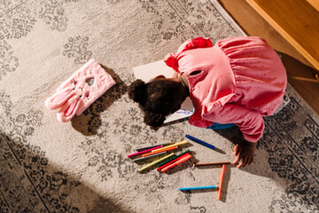 African american girl sitting on floor and drawing at home