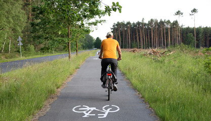 Kierownica roweru, rowerzysta na ścieżce rowerowej w lesie.