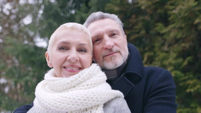 Middle-aged couple hugging in winter park, romantic mood, happy relationship