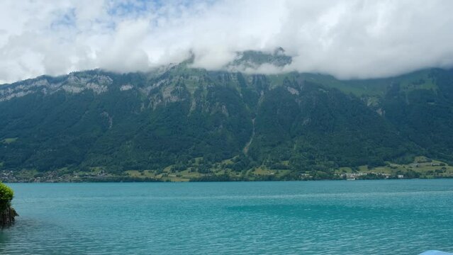 A handheld with noise effect panning footage of turquoise Lake Brienz with land insight.