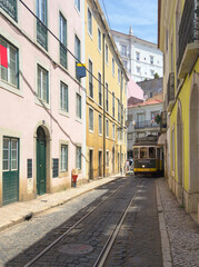 The tram runs along narrow street of Alfama district. Lisbon, Portugal.