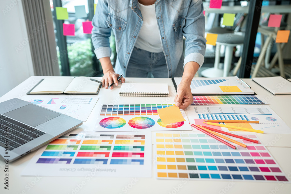 Poster Young creative graphic designer working on color selection and drawing on graphics tablet at workplace, Color swatch samples chart for selection coloring in inspiration to create new collection