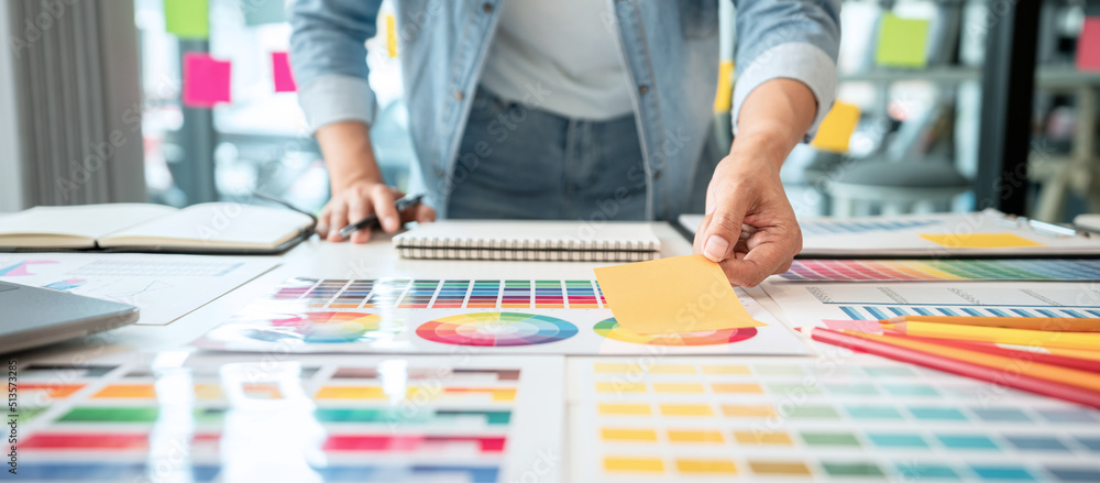 Poster Young creative graphic designer working on color selection and drawing on graphics tablet at workplace, Color swatch samples chart for selection coloring in inspiration to create new collection