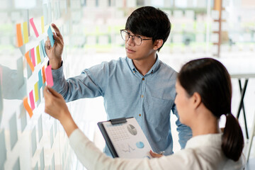 Two business executive team holding and taking notes keyword on board wall to brainstorm about a...