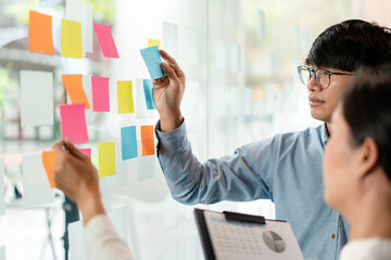Two business executive team holding and taking notes keyword on board wall to brainstorm about a...