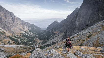 Fototapeta na wymiar Hiker enjoying the view on alpine valley with big mountains and autumn colours, Slovakia, Europe