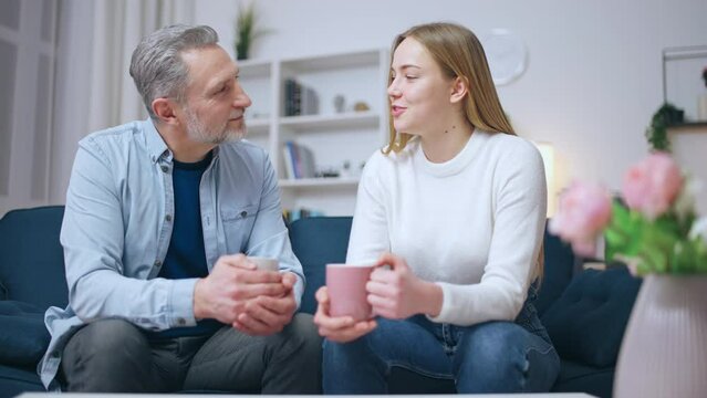 Father and daughter drinking tea together, sharing thoughts, family reunion