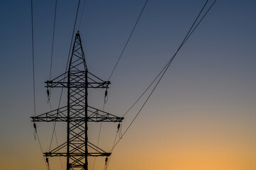 Group silhouette of transmission towers (power tower, electricity pylon, steel lattice tower) at twilight in US