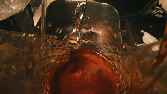 the barman pours a red cocktail into a whiskey glass
