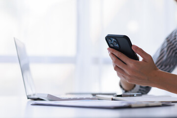 Cropped shot of a professional businesswoman holding smartphone in modern office room