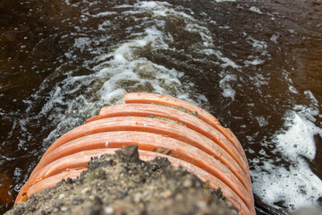 A stream of water flows from a large flexible pipe - hose.