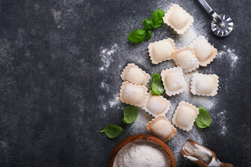 Obraz na płótnie Canvas Ravioli Italian food. Tasty homemade with flour, tomatoes, eggs and greens basil on dark background. Food cooking ingredients background. Top view.