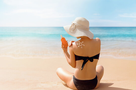 Beautiful woman in bikini applying sun cream on tanned shoulder. Sun protection. Skin and body care.