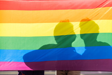 Rainbow lgtbi flag with an unrecognizable couple of boys in the background