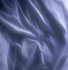 Top view of blue fabric background. Wrinkled natural linen material. Smooth satin or velvet sheets with gentle folds. Closeup texture of luxurious grey cloth. Abstract dark silk patterns or creases