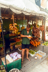 Male model, traveler drinking coconut against the backdrop of an exotic fruit shop, holiday landscape.