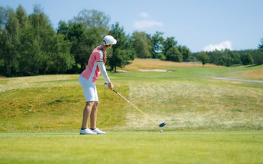 Pretty sportswoman hitting the ball with golf club. Professional female golfer holding golf club on...